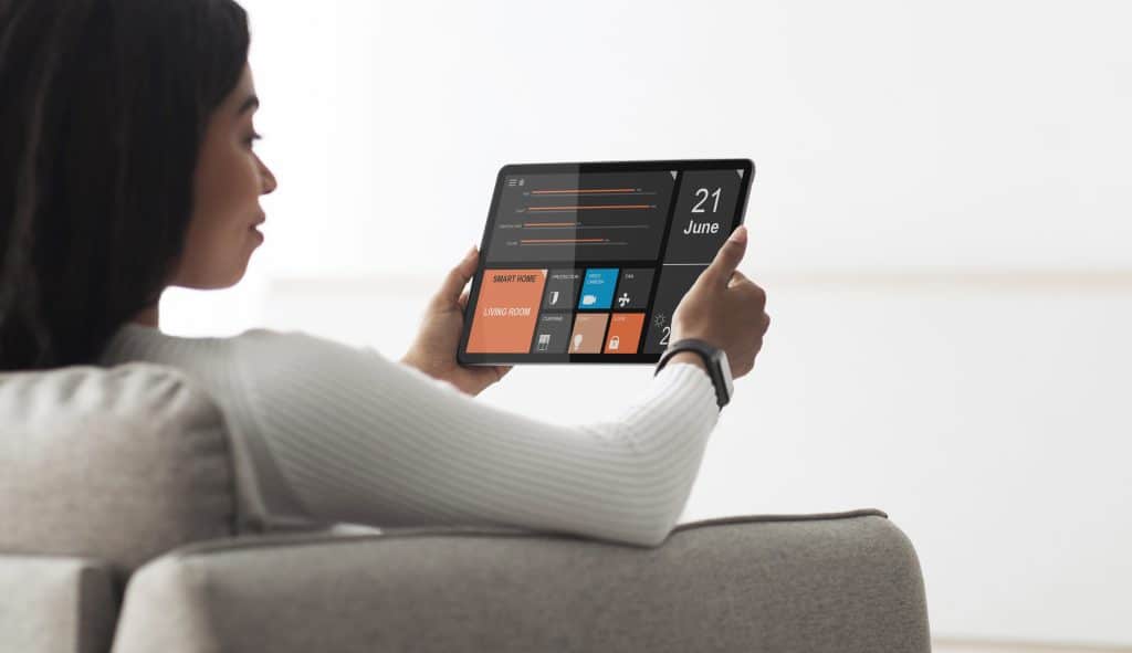 image of young woman adjusting her HVAC zoning systems on her tablet